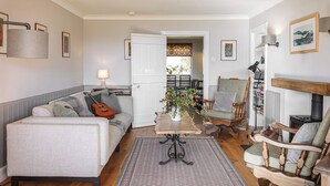 Ein gemütliches Wohnzimmer mit Sofa, Sessel und einem Couchtisch mit Blumen.
