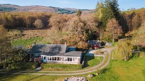 Ein Haus mit einer breiten Veranda, einem steinernen Weg und Blick auf die umliegenden Hügel.