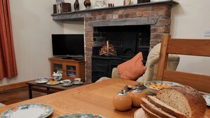 A dining area with a wooden table set for a meal, a fireplace, and a television in the background.