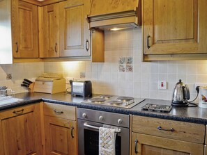 A kitchen with wooden cabinets, a stainless steel stove, a toaster, and a kettle.