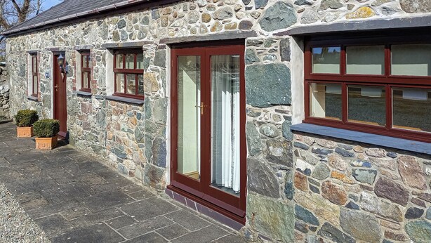 A stone building with a large window, a door, and a small window.