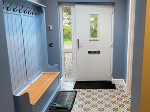 A hallway with a white door, a bench, and patterned floor tiles. - 3 bedroom accommodation in Taynuilt (Taynuilt)