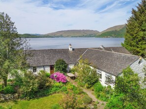 A house with a stone roof, surrounded by lush greenery and a view of a lake. - 3 bedroom accommodation in Taynuilt (Taynuilt)