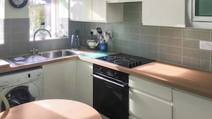 Una cocina con pileta, cocina, horno y un reloj en la pared.