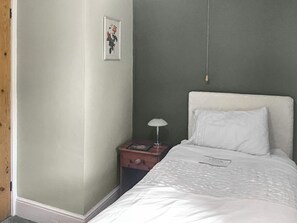 Une chambre à coucher avec un lit, une table de chevet, une lampe et un tableau encadré au mur.
