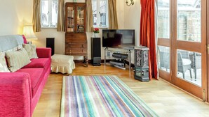 A cozy living room with a red sofa, a wooden cabinet, a television, and a glass coffee table.