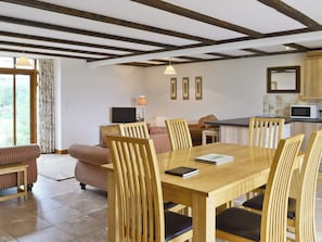 A dining area with a wooden table and chairs, a television, and a kitchen area with a microwave.