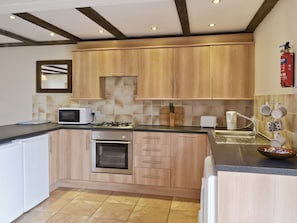 Une cuisine compacte dotée de meubles en bois, d’un four à micro-ondes, d’un grille-pain et d’une cuisinière à gaz.