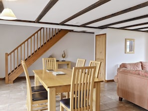 Un coin repas avec une table et des chaises en bois, un escalier et un canapé.