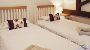 Two single beds with wooden headboards, white bedding, and a nightstand with a lamp. - 3 bedroom accommodation in Catfield (Catfield)