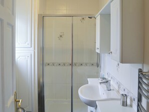 Un bagno con cabina doccia in vetro, un lavandino bianco e uno specchio sopra al lavandino.