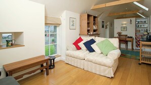 Una sala de estar acogedora con un sofá, un banco de madera y un comedor con mesa y sillas.