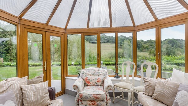 A conservatory with a glass roof, furnished with sofas and chairs, offering a view of a lush garden. - 6 bedroom accommodation in Highley, near Bridgenorth (Highley, near Bridgenorth)