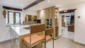 A modern kitchen with a central island, wooden cabinets, and a bar area with leather chairs. - 6 bedroom accommodation in Highley, near Bridgenorth (Highley, near Bridgenorth)