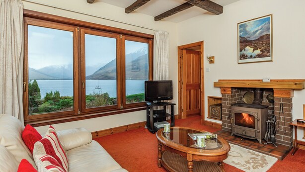 Una sala de estar acogedora con un ventanal grande, una chimenea y un televisor.