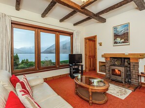 A cozy living room with a large window, a fireplace, and a television. - 2 bedroom accommodation in Ratagan, By Kyle of Lochalsh (Ratagan, By Kyle of Lochalsh)