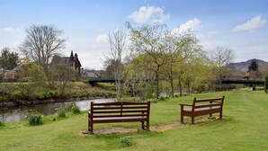 Un parc verdoyant avec deux bancs en bois et un petit ruisseau.