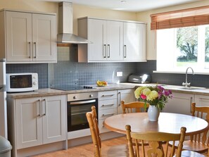 A modern kitchen with white cabinets, a microwave, a toaster, and a dining table with chairs.