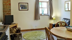 A cozy living room with a fireplace, a dining table, and a TV. - 2 bedroom accommodation in Sewerby, near Bridlington (Sewerby, near Bridlington)