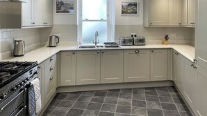 Une cuisine moderne avec des meubles gris, une cuisinière à gaz, un évier et deux grille-pains fixés au mur.