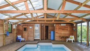 Une cabane en bois avec une piscine, un sauna et une vue sur l’extérieur.