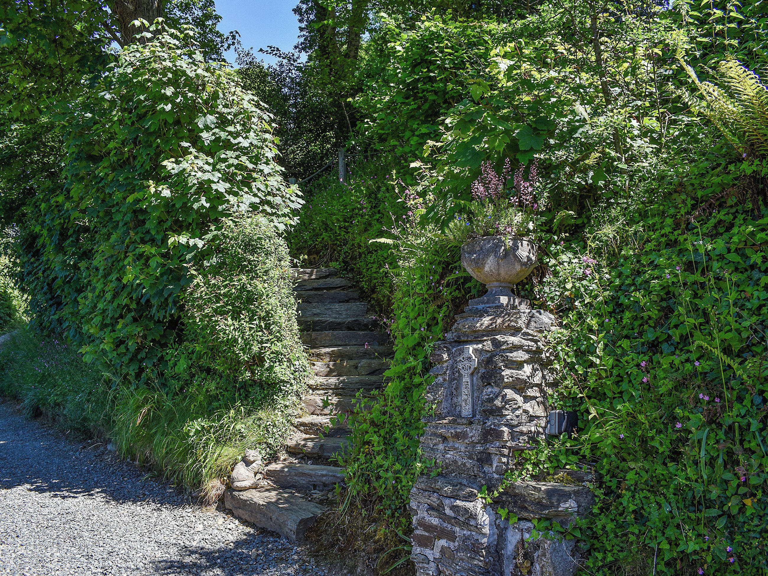 A stone staircase surrounded by dense greenery and a decorative urn.