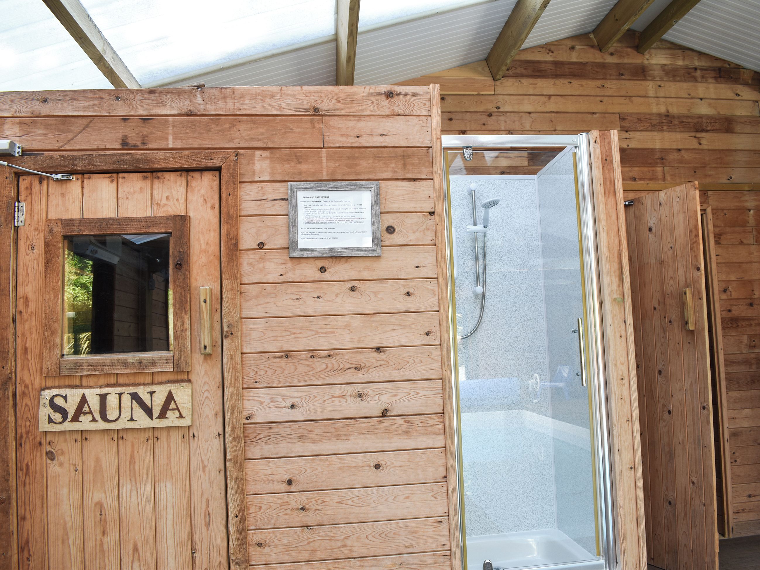 Eine Holzsauna mit Glastür, Fenster und einem Schild mit der Aufschrift 'SAUNA'.