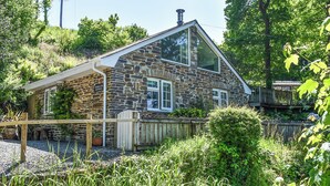 Un bâtiment en pierre avec un toit en pente, une terrasse en bois et une enseigne sur laquelle on peut lire « HAVRE DE PAIX EN FORÊT ».