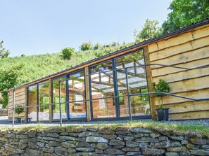 Un edificio moderno con grandes ventanales y un muro de piedra en la base.