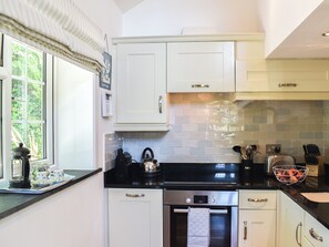 A kitchen with white cabinets, a black countertop, and a stainless steel oven.