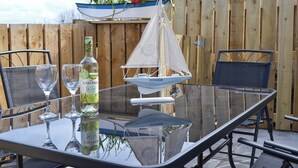 A glass table with two wine glasses and a bottle of liquor. A small sailboat model is hanging above the table. - 3 bedroom accommodation in New Quay (New Quay)