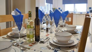 A dining table set with blue napkins, wine bottles, and dinnerware. - 3 bedroom accommodation in New Quay (New Quay)