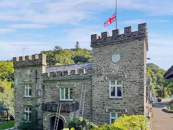 A stone building with a flag, windows, and a tower.