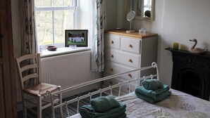 Un dormitorio con cama, una silla, cómoda, espejo y chimenea.