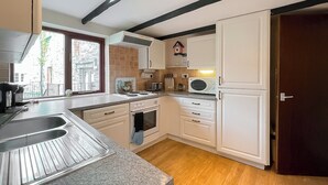 A kitchen with white cabinets, a microwave, a stove, and a sink.