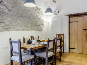 A dining area with a wooden table, chairs, a clock, and pendant lights. - The Threshing Barn - HSSW (Patchole, near Barnstaple)