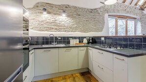 A modern kitchen with a stone wall, a gas stove, and a window.