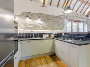 Une cuisine moderne avec un mur en pierre, une cuisinière à gaz et une fenêtre.