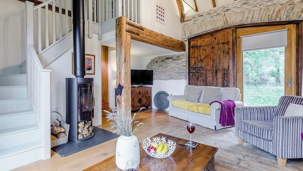 A spacious living room with a fireplace, a staircase, a large window, and a cozy seating area.