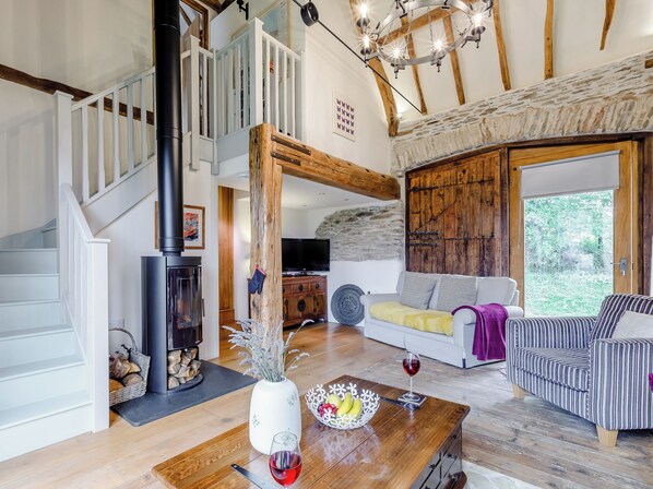 A spacious living room with a fireplace, a staircase, a large window, and a cozy seating area.