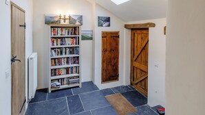 A hallway with a bookshelf, a wooden door, and a skylight.