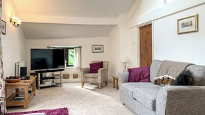 A spacious living room with a flat-screen TV, a sofa, a chair, and a small table. - 3 bedroom accommodation in Starbotton, near Skipton (Starbotton, near Skipton)