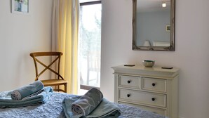 A bedroom with a bed, a chair, a dresser, a mirror, and a window with curtains. - 3 bedroom accommodation in Starbotton, near Skipton (Starbotton, near Skipton)