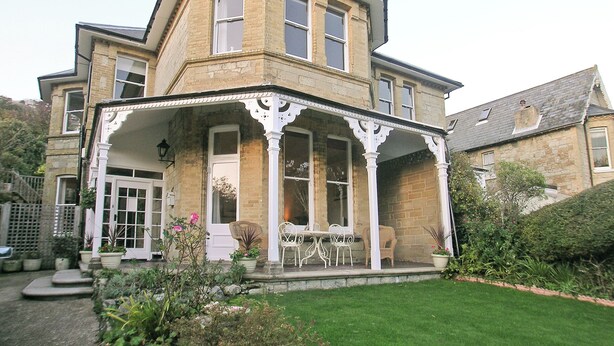 A two-story house with a porch, a front door, and a small garden area. - 3 bedroom accommodation in Ventnor (Ventnor)
