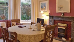 A dining room with a table set for four, a fireplace, and a window with curtains. - 3 bedroom accommodation in Ventnor (Ventnor)