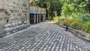 A cobblestone pathway leading to a building with stone walls and a wooden fence. - 1 bedroom accommodation in Curbar, near Bakewell (Curbar, near Bakewell)