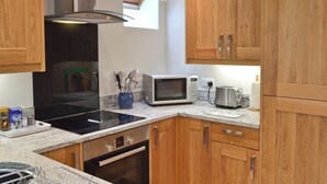 A modern kitchen with wooden cabinets, a microwave, a toaster, and a built-in oven. - 1 bedroom accommodation in Curbar, near Bakewell (Curbar, near Bakewell)