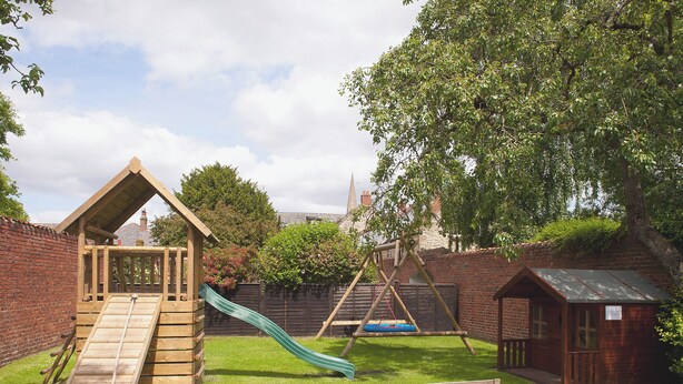 A wooden play structure with a slide, a small wooden house, and a brick wall. - 3 bedroom accommodation in Pickering (Pickering)