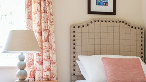 A bedroom with a bed, a nightstand with a lamp, a headboard with buttons, and a framed picture on the wall. - 3 bedroom accommodation in Pickering (Pickering)