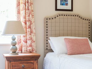 A bedroom with a bed, a nightstand with a lamp, a headboard with buttons, and a framed picture on the wall. - 3 bedroom accommodation in Pickering (Pickering)